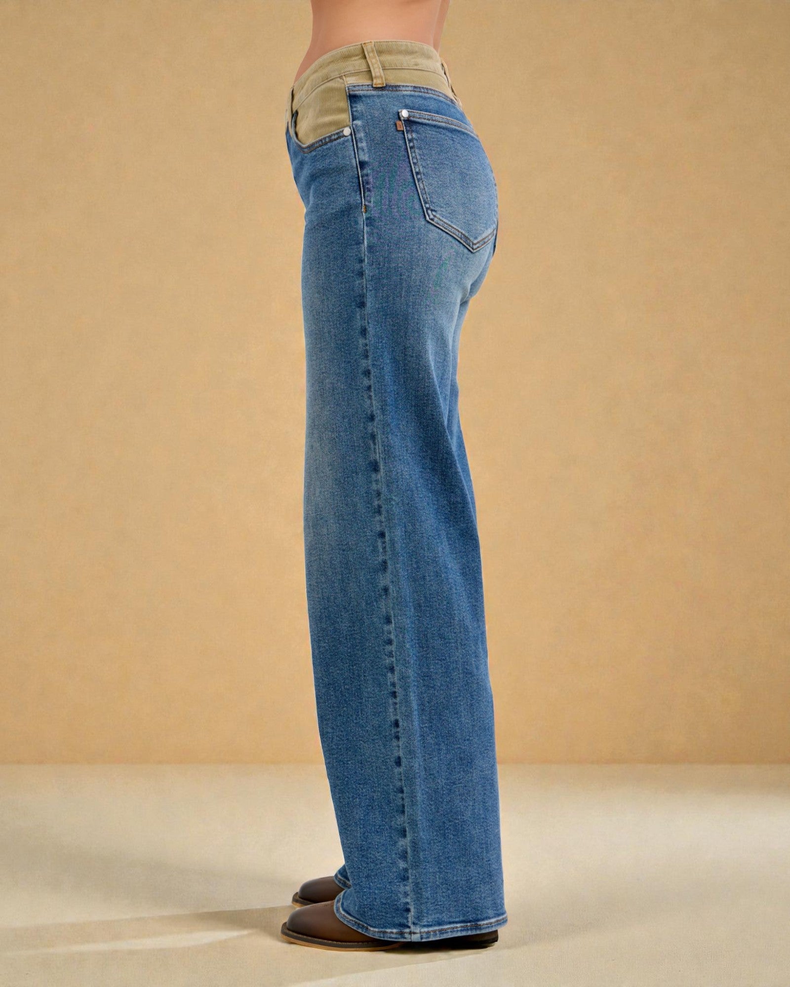Person wearing blue jeans with a beige patch on a beige background