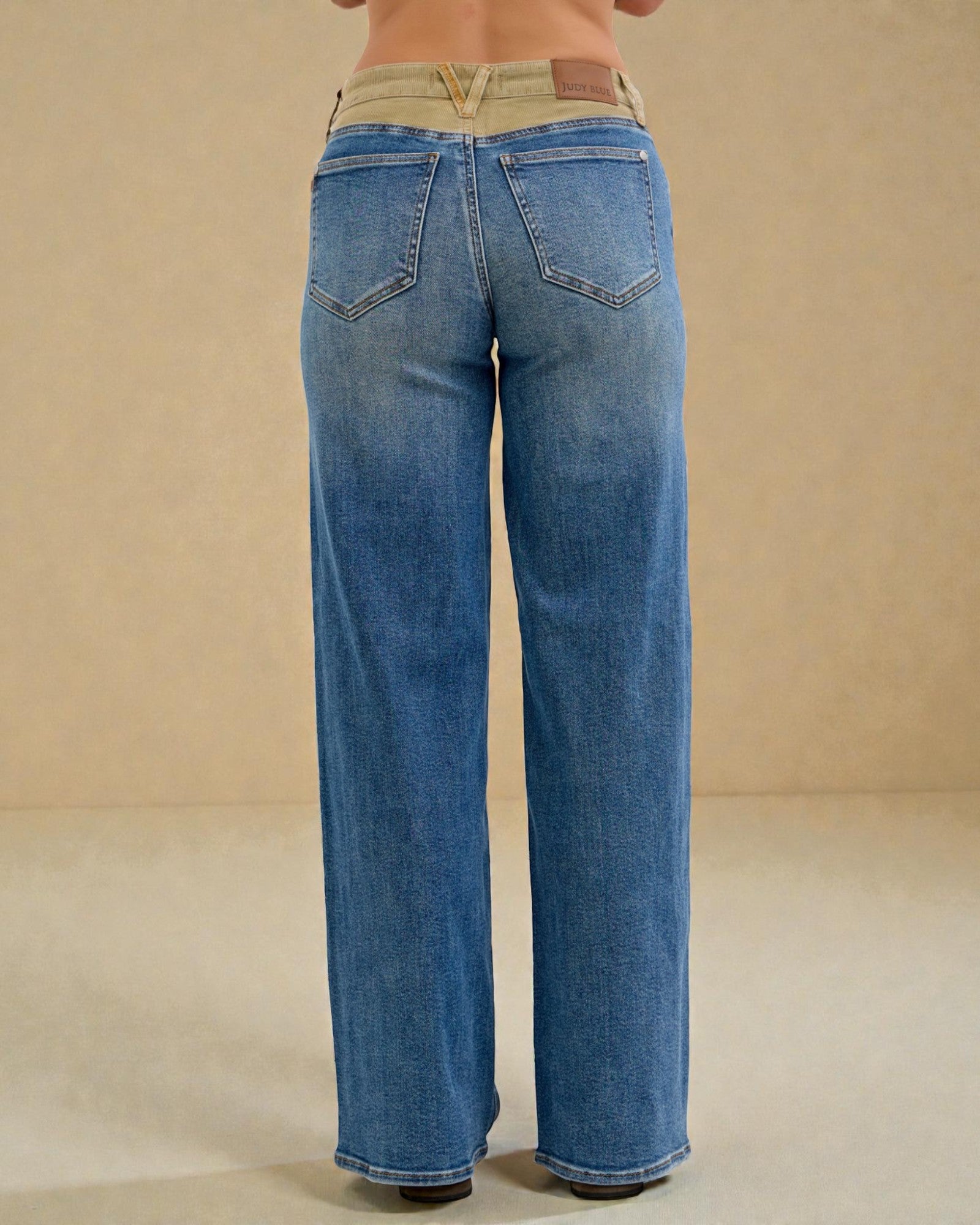 Blue jeans worn by a person on a beige background