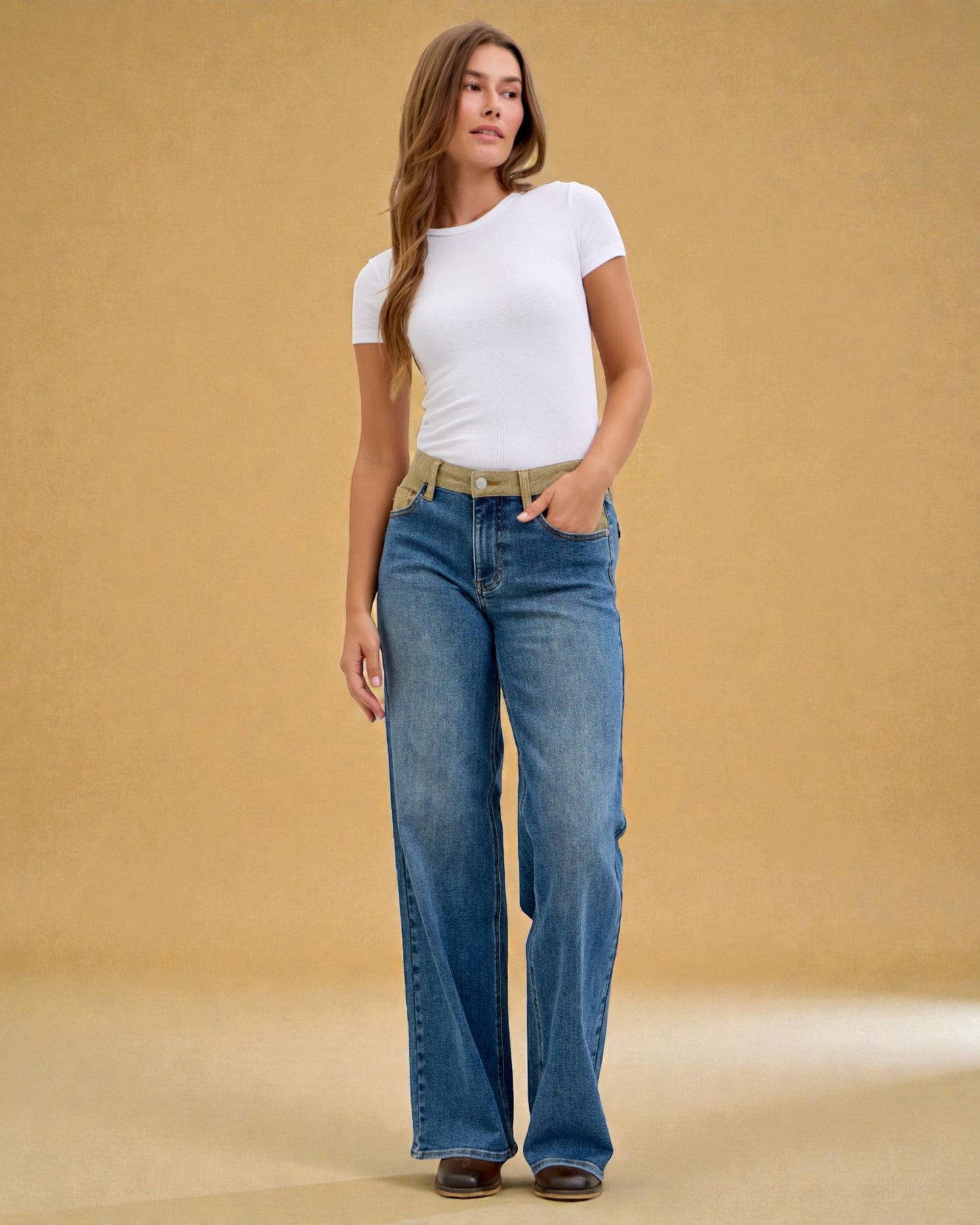 Woman wearing a white t-shirt and blue jeans against a beige background