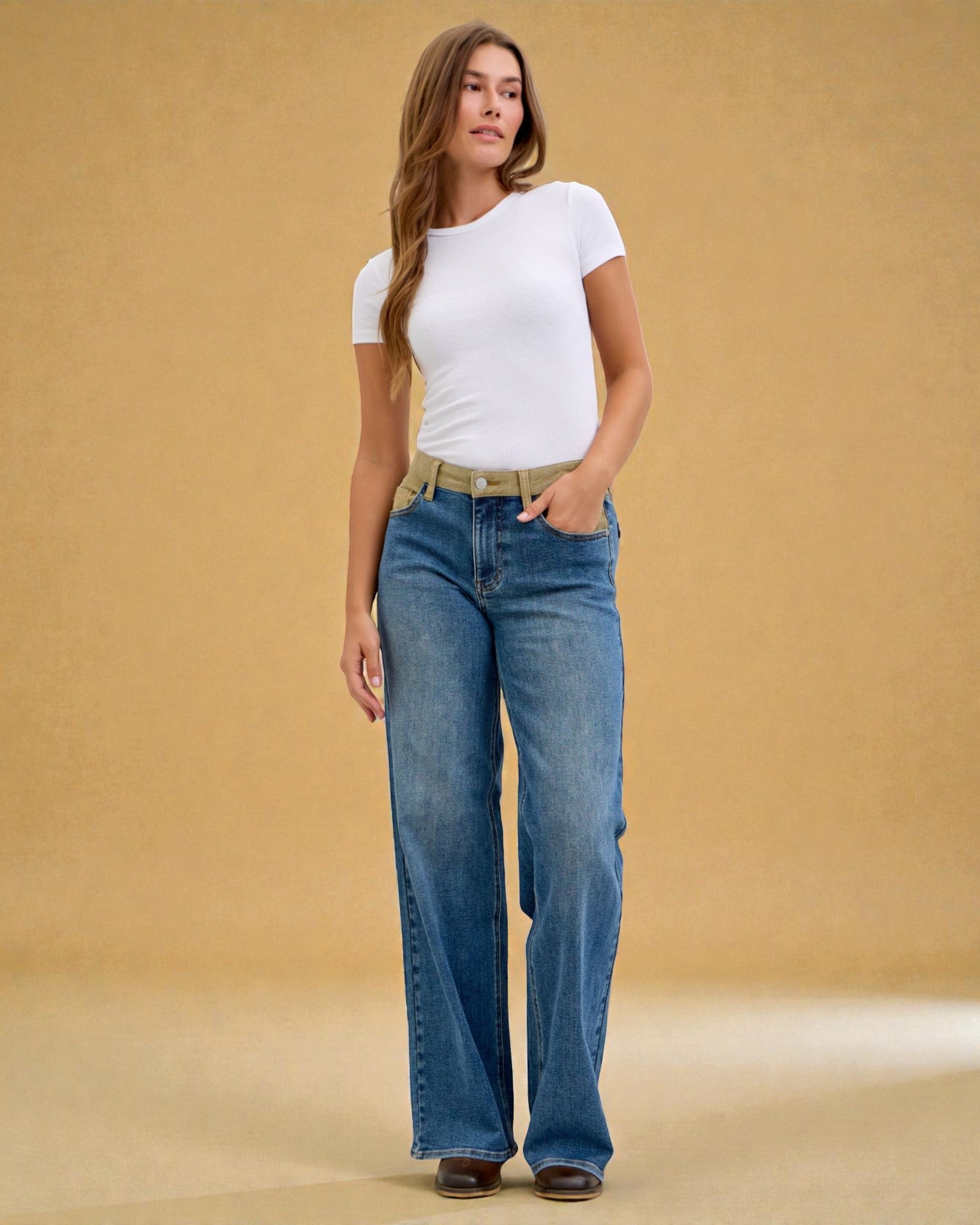 Woman wearing a white t-shirt and blue jeans against a beige background