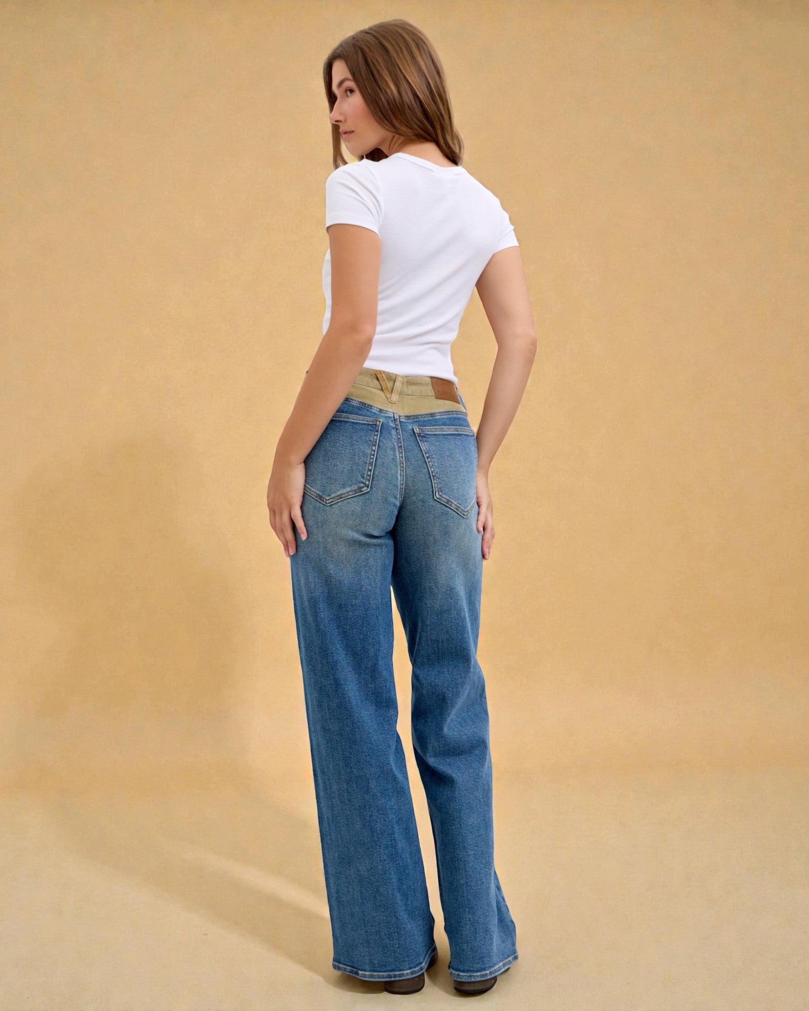 Woman wearing blue jeans and a white t-shirt on a beige background