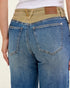 Close-up of blue jeans with a visible brand label on a plain background