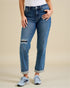 Person wearing blue jeans with patch details on a beige background