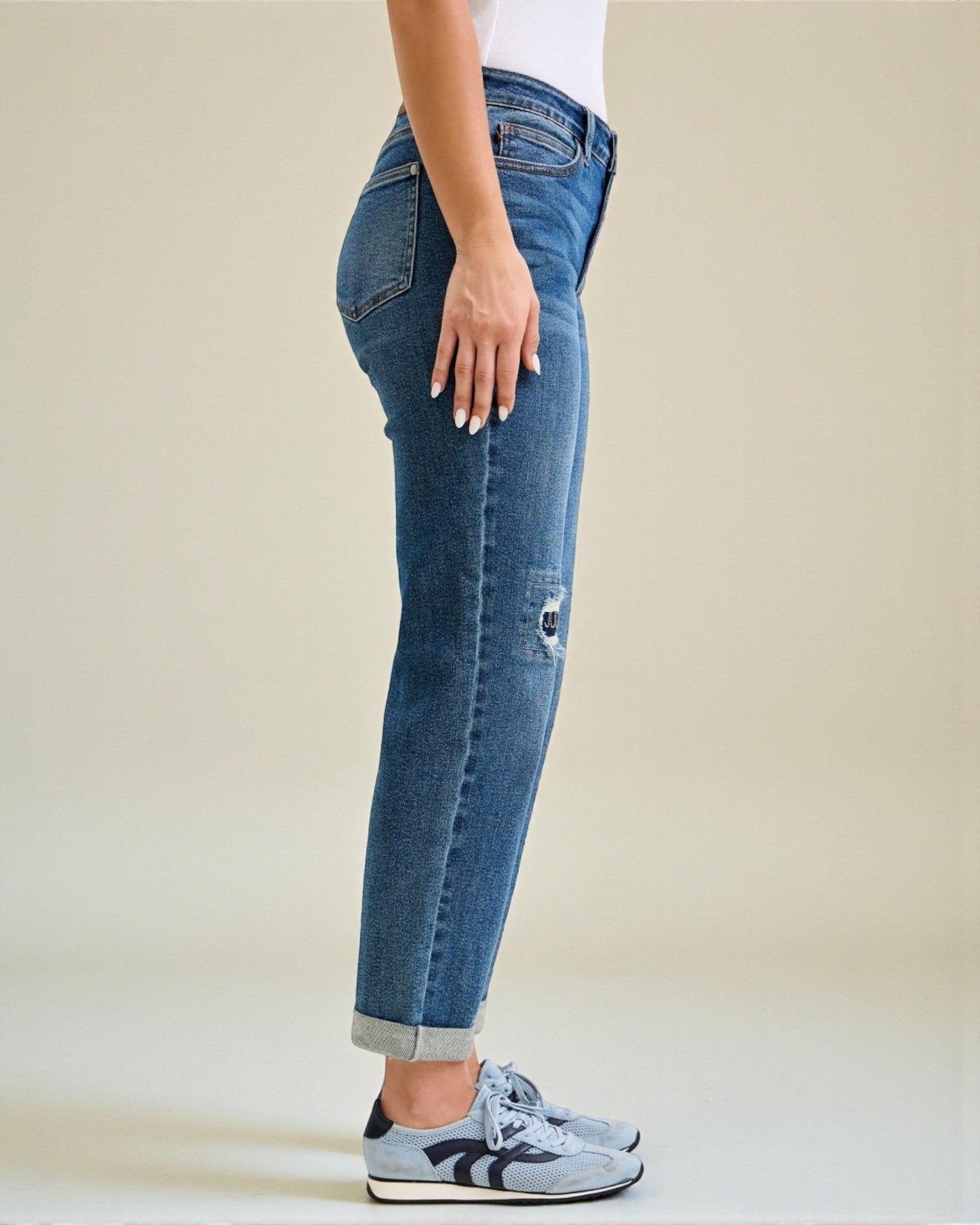 Person wearing blue jeans and sneakers on a plain background