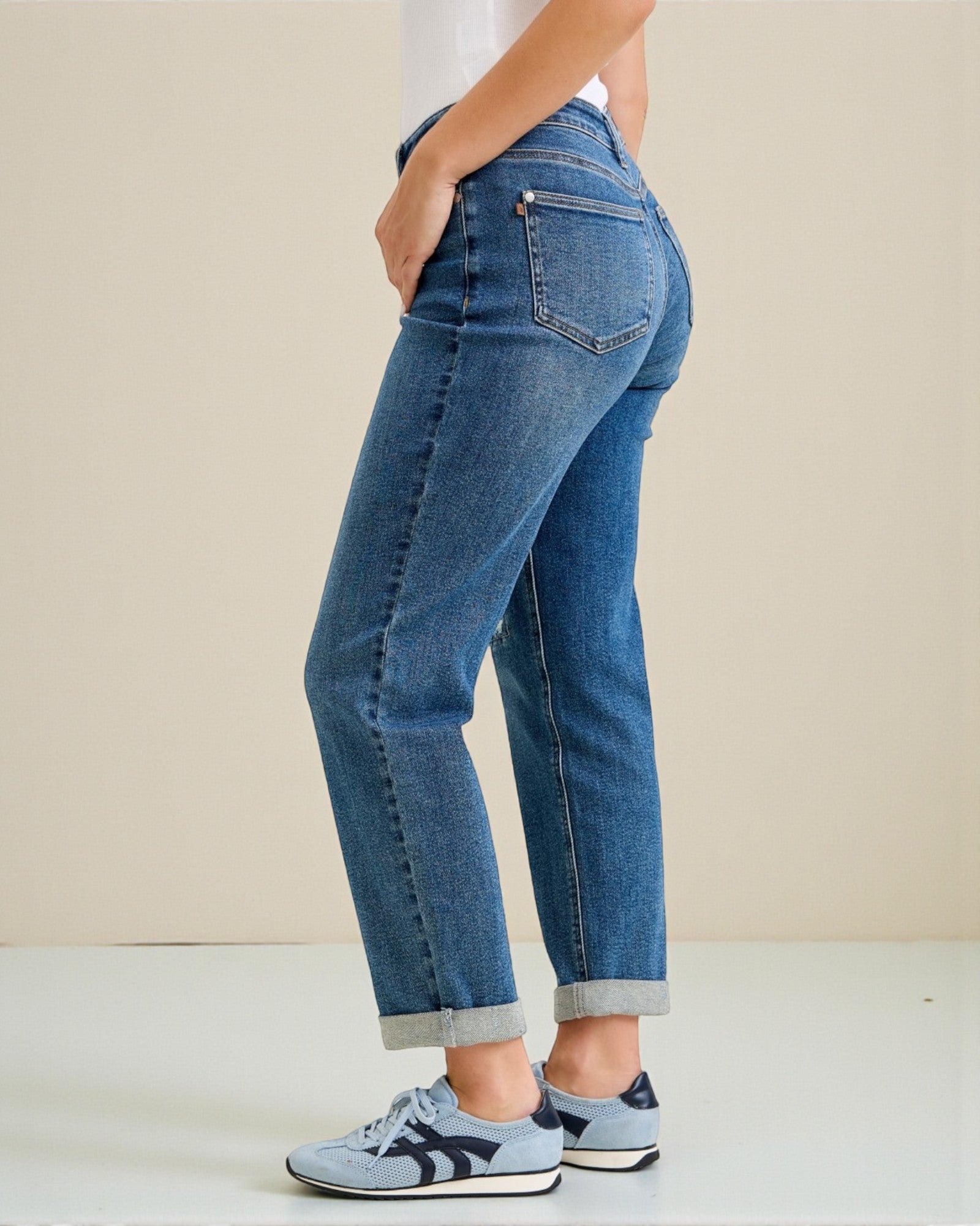 Person wearing blue jeans and sneakers on a plain background