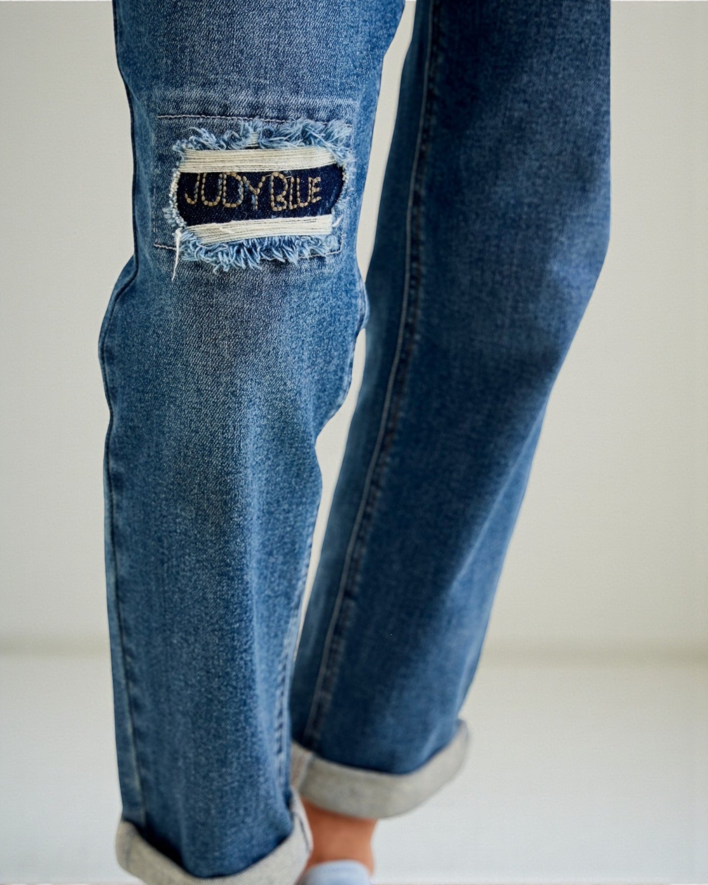 Blue jeans with a brand label on a plain background