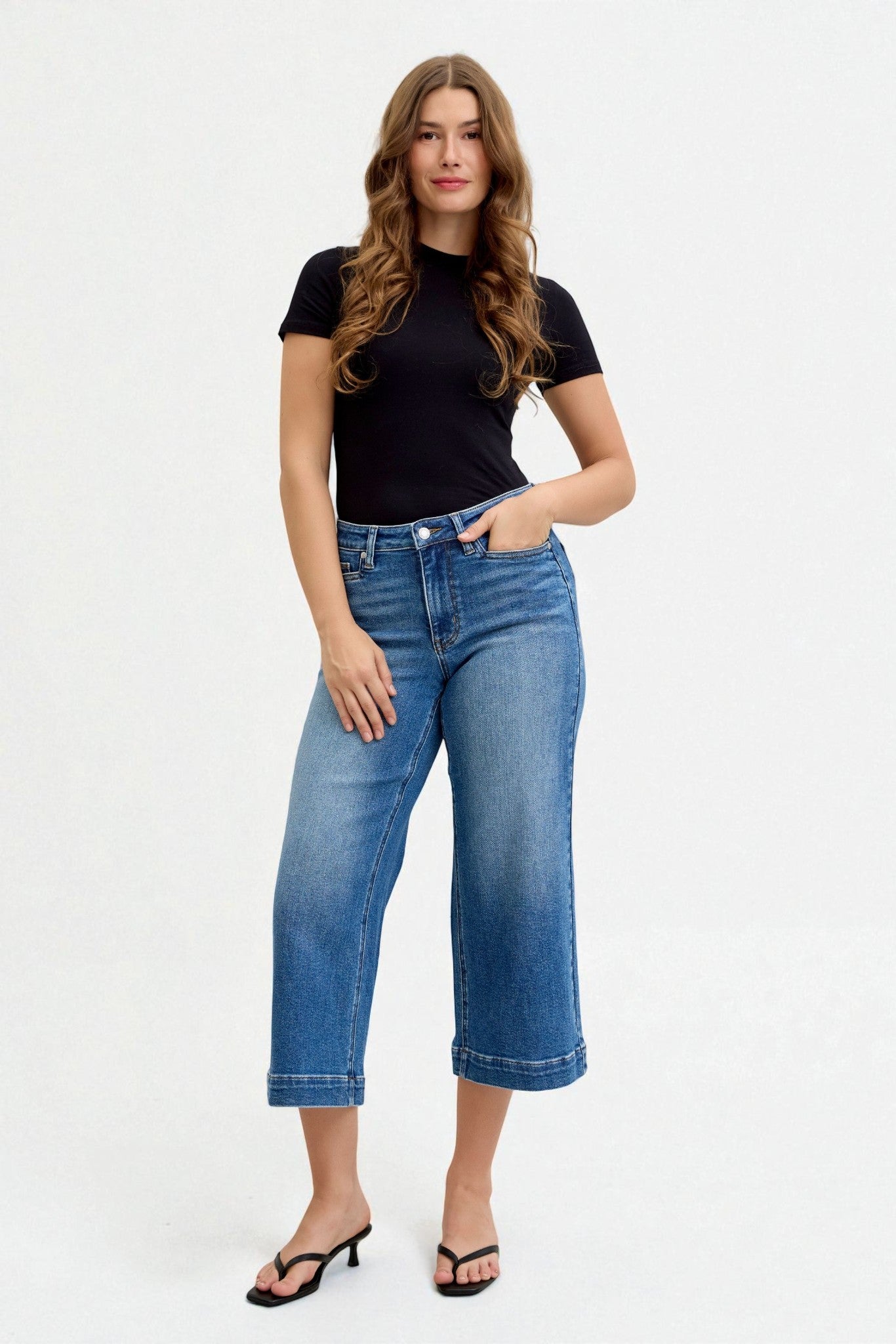 Woman wearing blue jeans and a black t-shirt on a white background