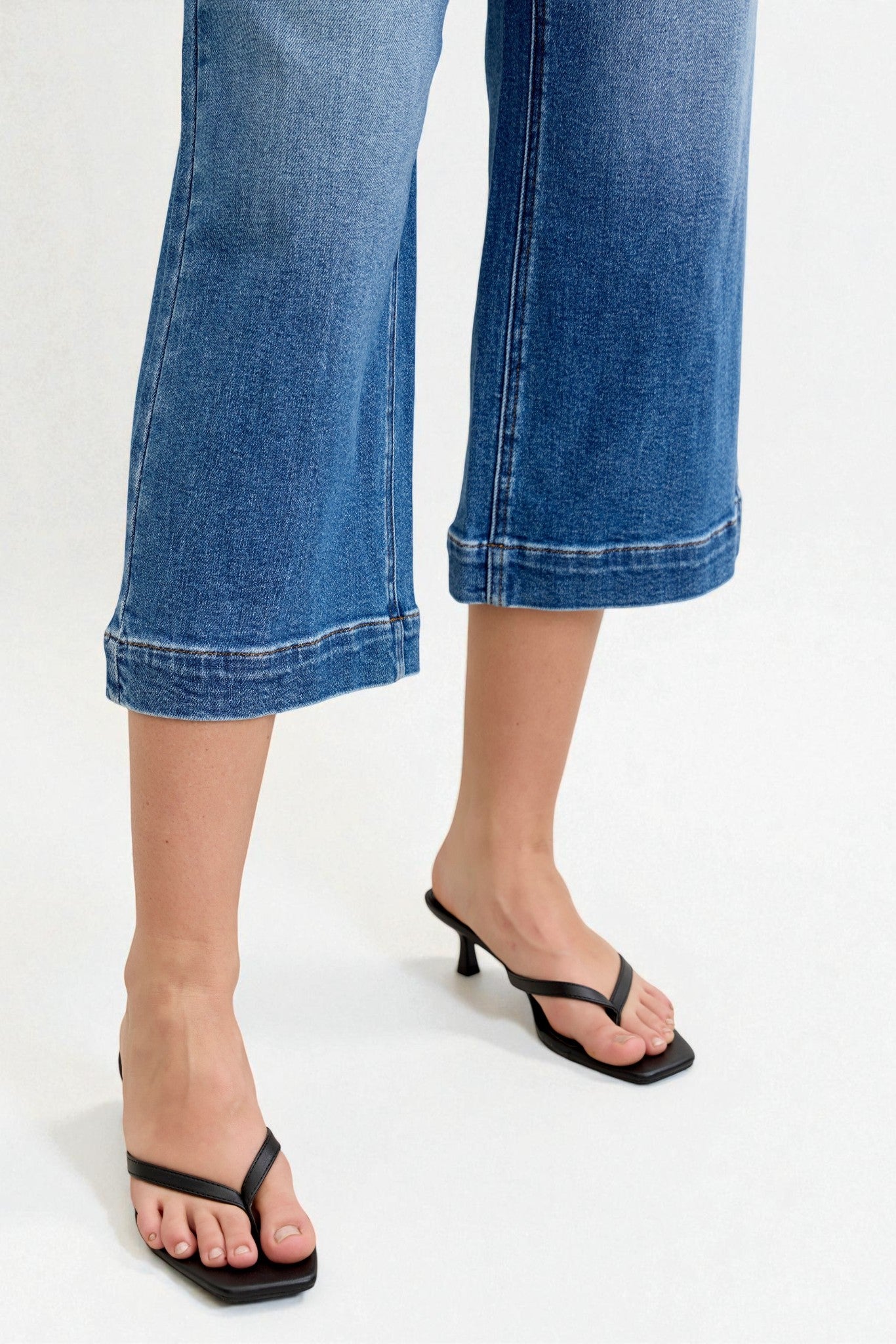 Blue jeans and black sandals on a white background