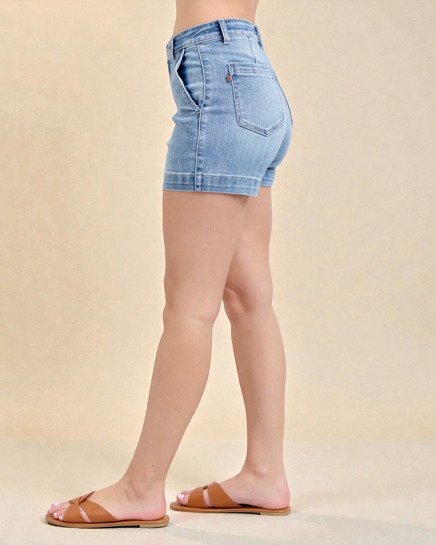 Denim shorts worn by a person on a beige background