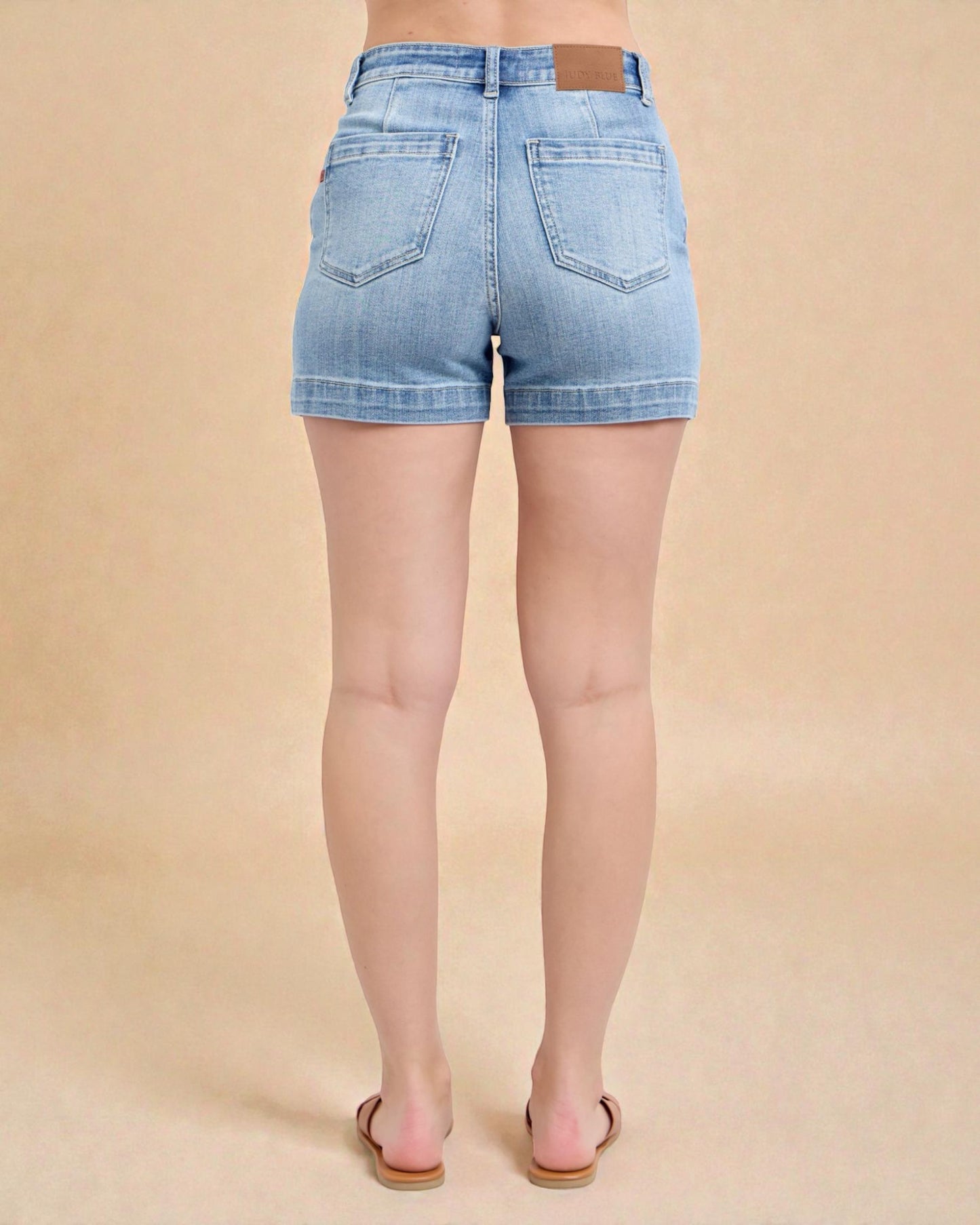 Light blue denim shorts worn by a person on a beige background