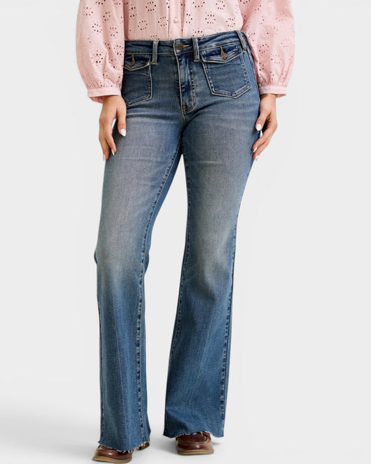 Person wearing blue flared jeans and a pink blouse on a white background