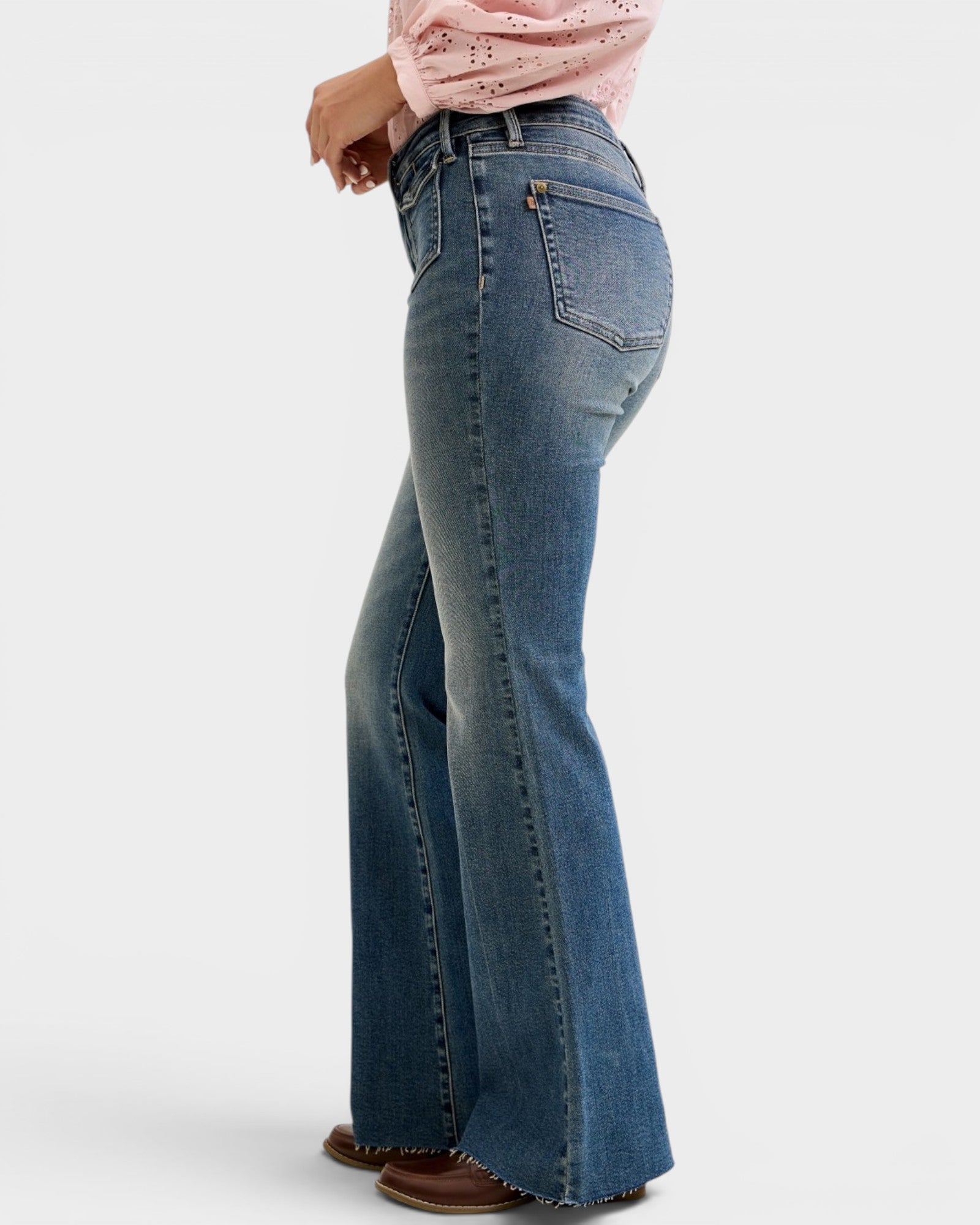 Person wearing blue flared jeans on a white background
