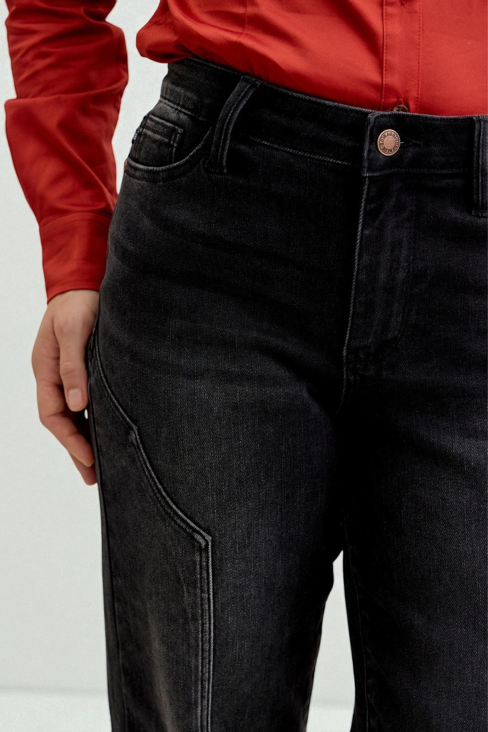 Person wearing black jeans with a red shirt on a white background