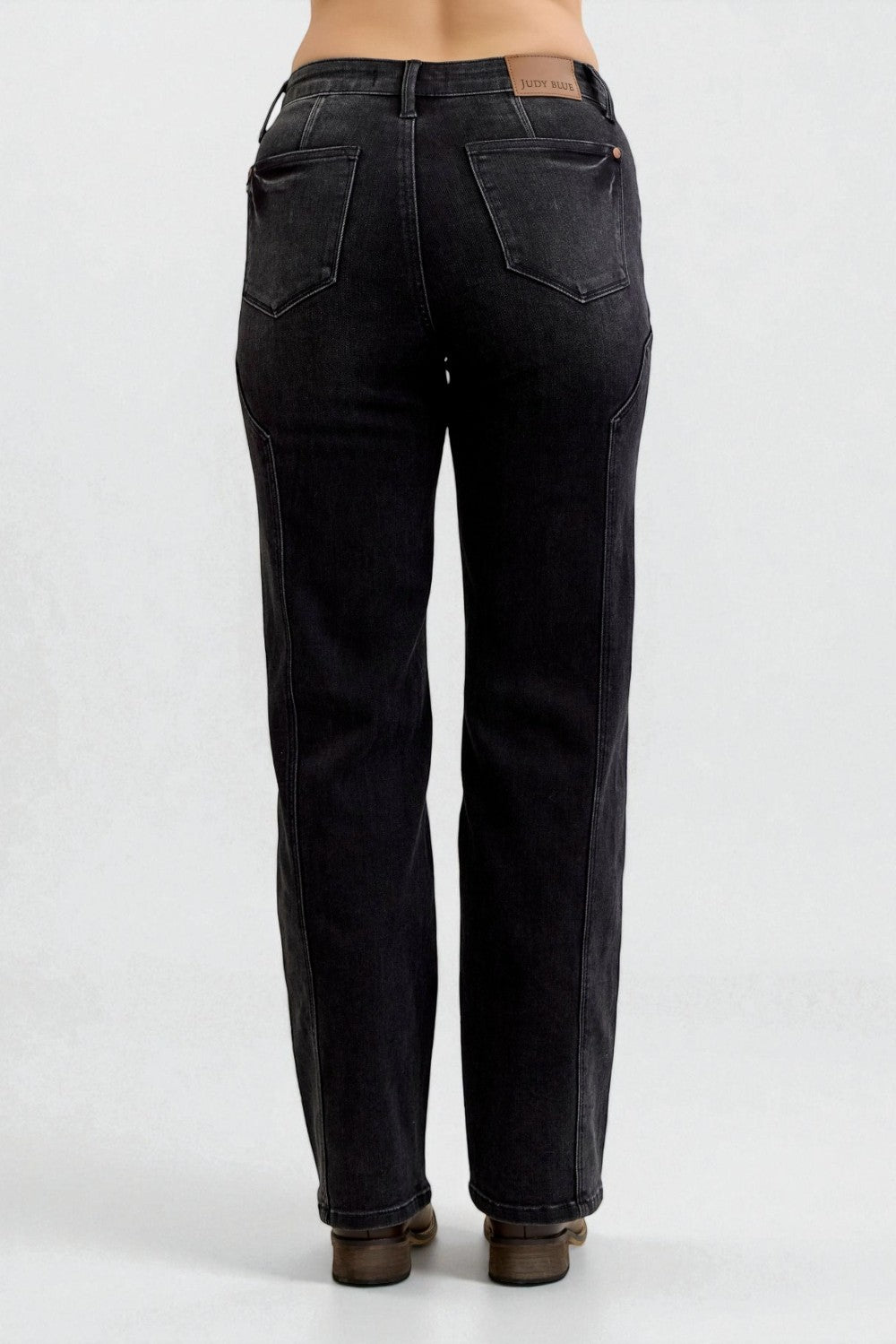 Black jeans worn by a person on a white background