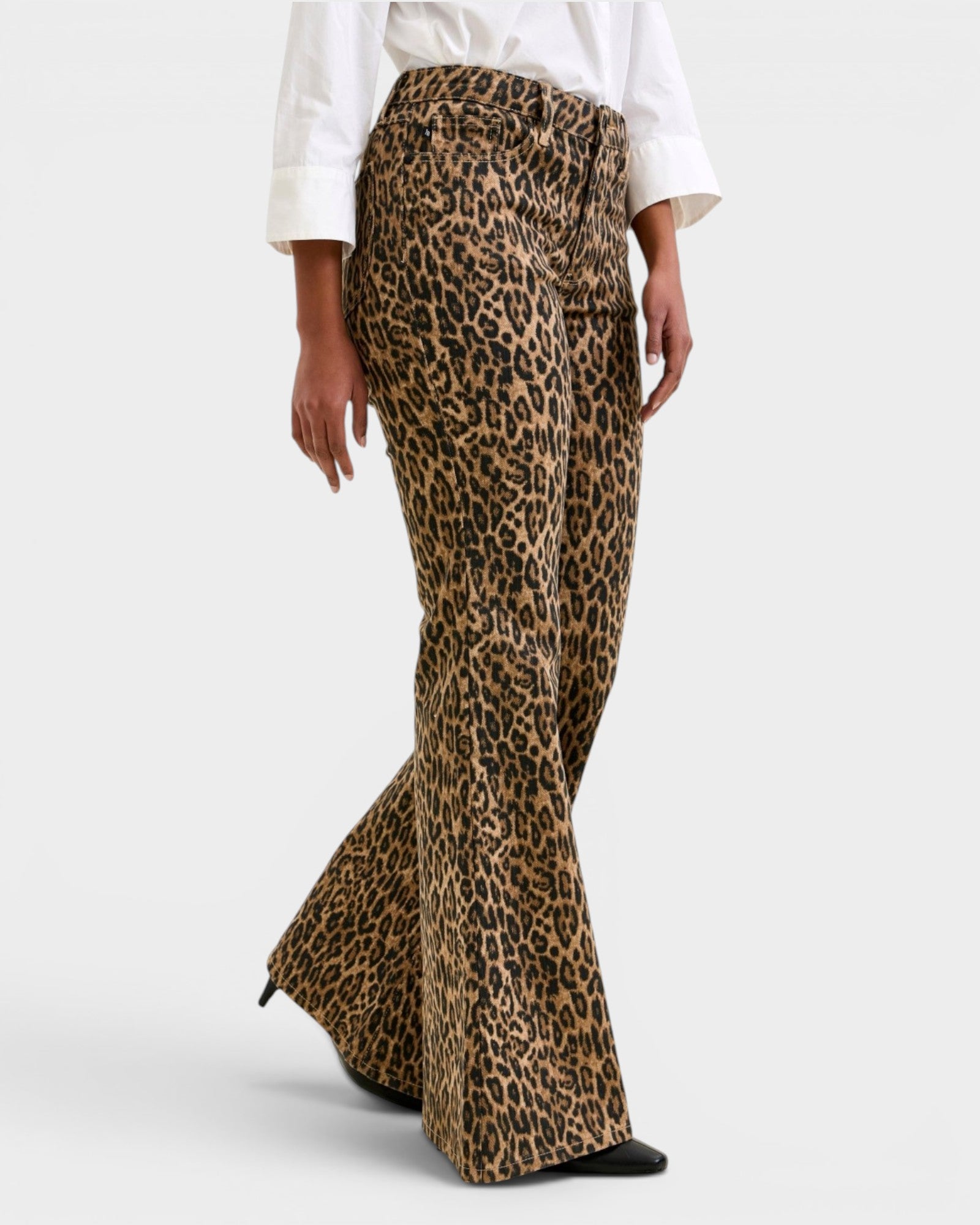 Leopard print flared pants worn with a white shirt on a light gray background