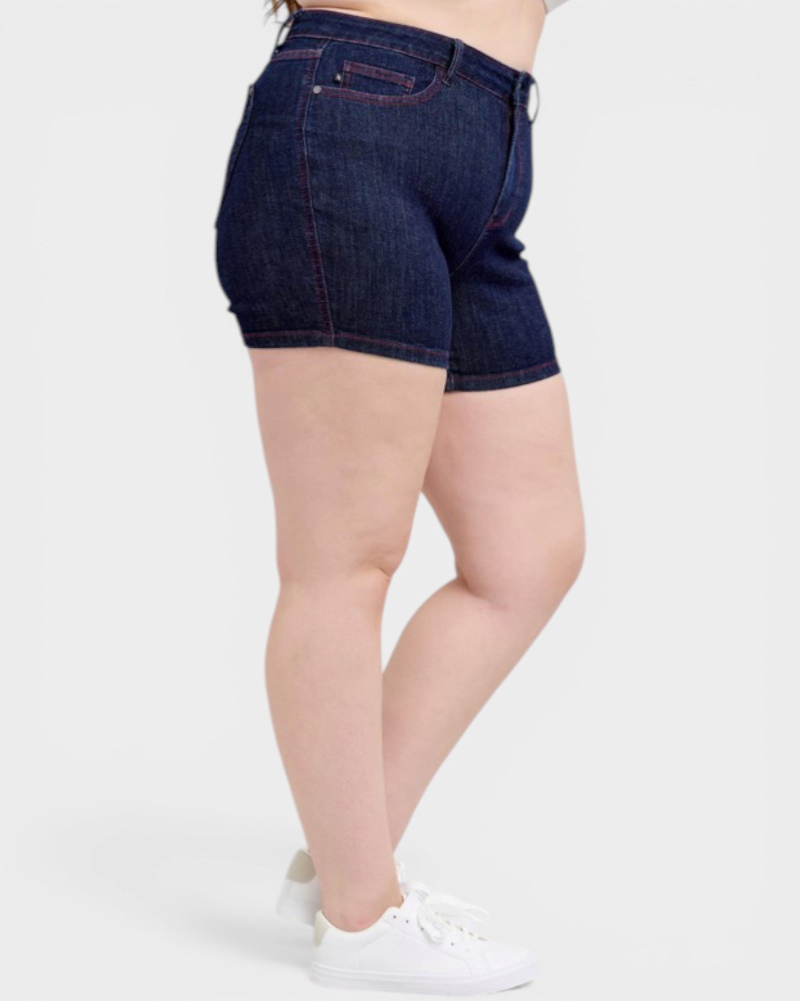 Person wearing dark blue denim shorts on a white background