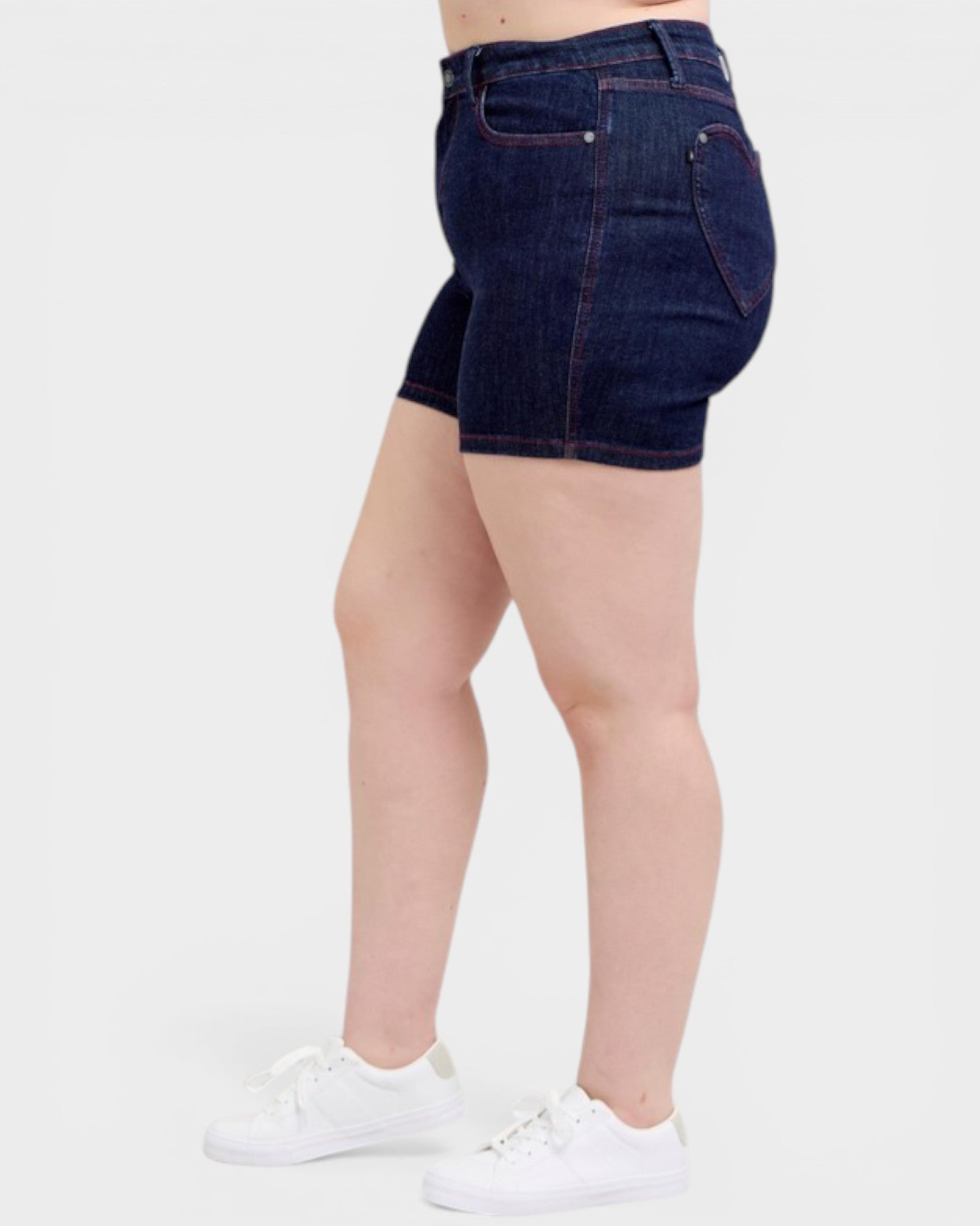 Person wearing dark blue denim shorts on a white background