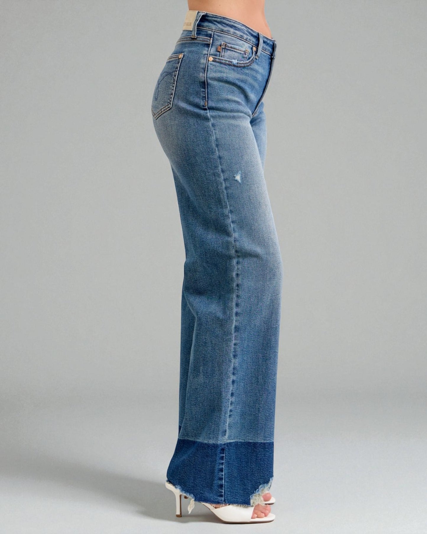 Blue jeans with a distressed hem on a gray background