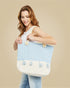 Woman holding a large blue and white checkered bag with decorative elements on a beige background