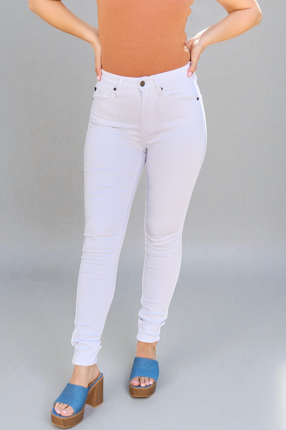 Person wearing white jeans and blue sandals on a gray background