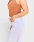 Person wearing a brown top and white pants on a light gray background