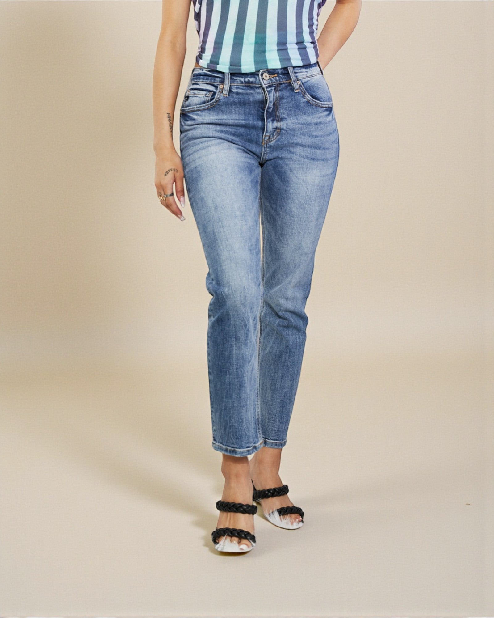 Person wearing blue jeans and a striped top on a beige background
