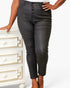 A model wearing black faux-leather cropped pants with a button-fly front, standing next to a white dresser.