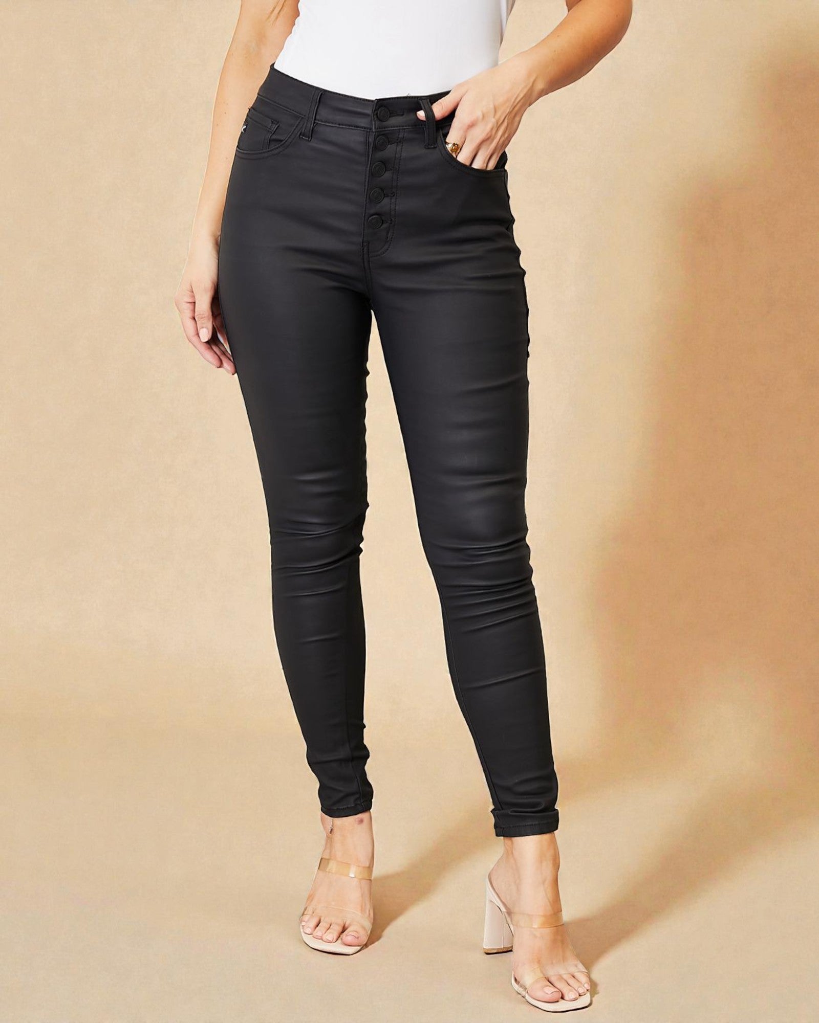 Person wearing black leather pants on a beige background