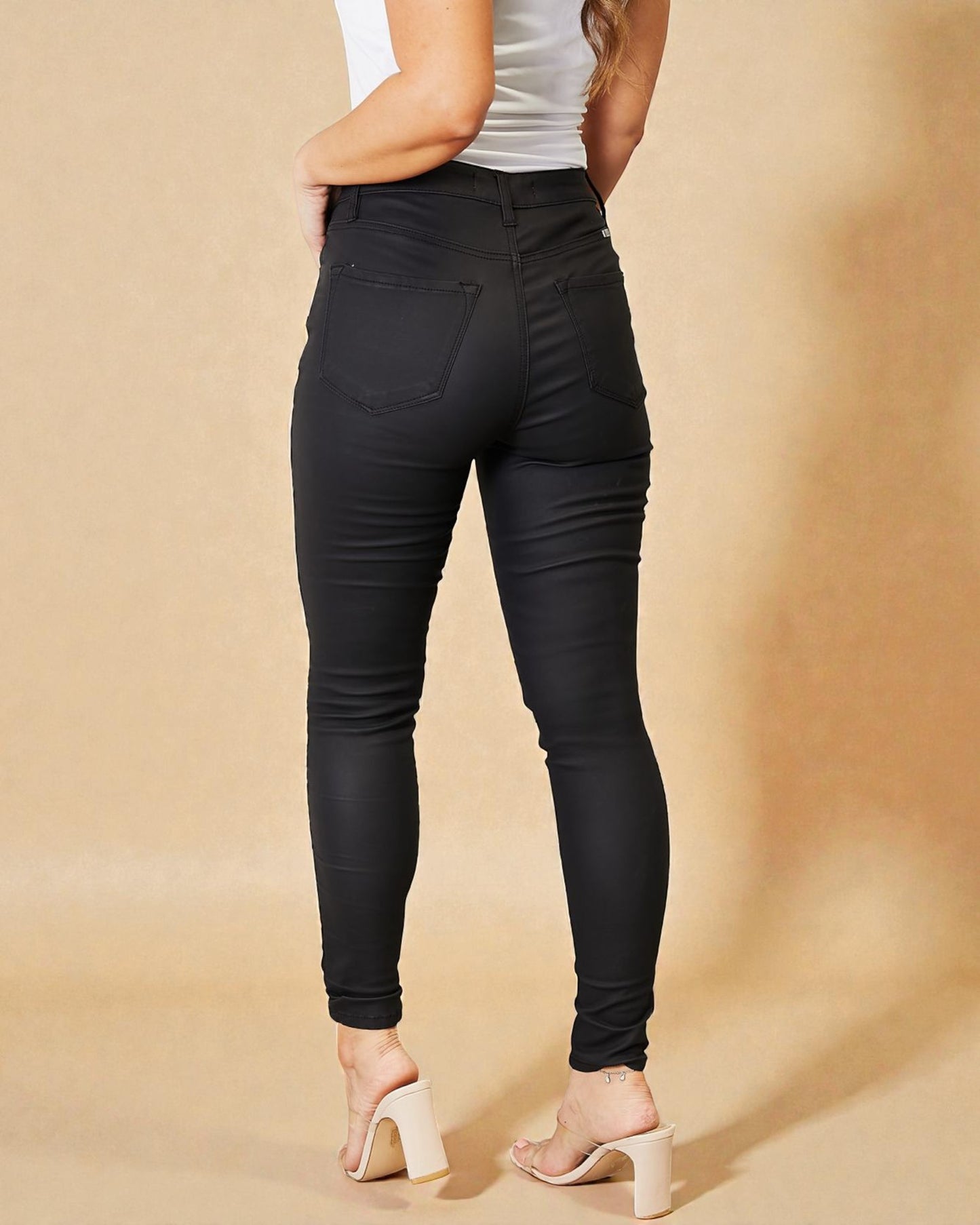 Person wearing black jeans on a beige background