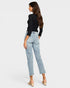 Woman wearing light blue jeans and a black top on a white background