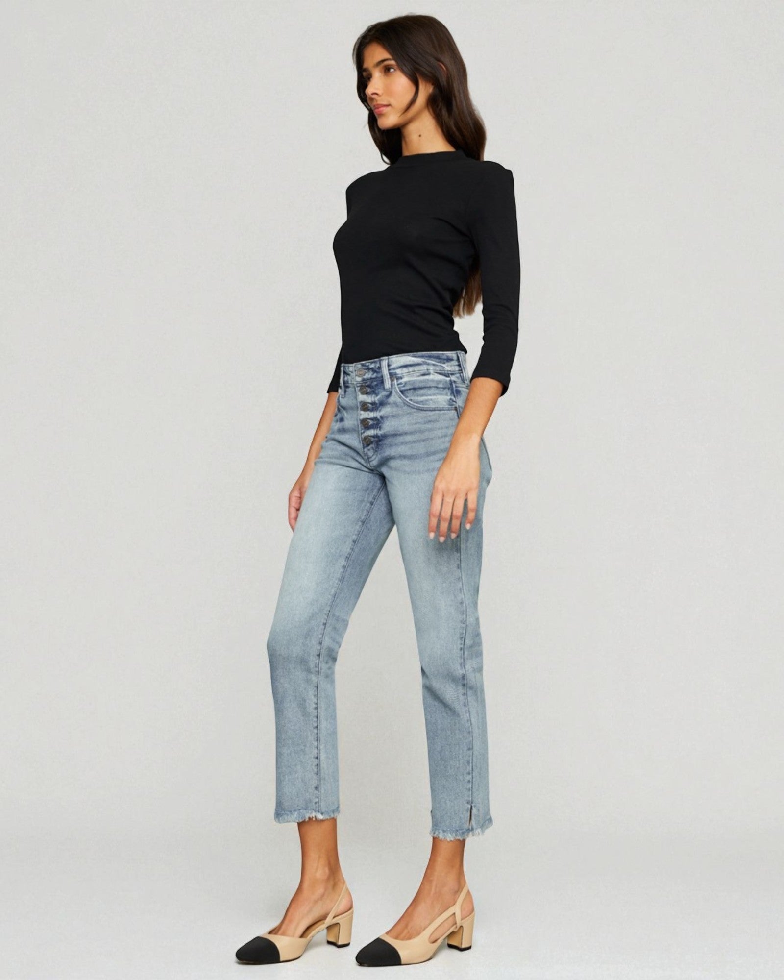 Woman wearing a black top and light blue jeans on a white background