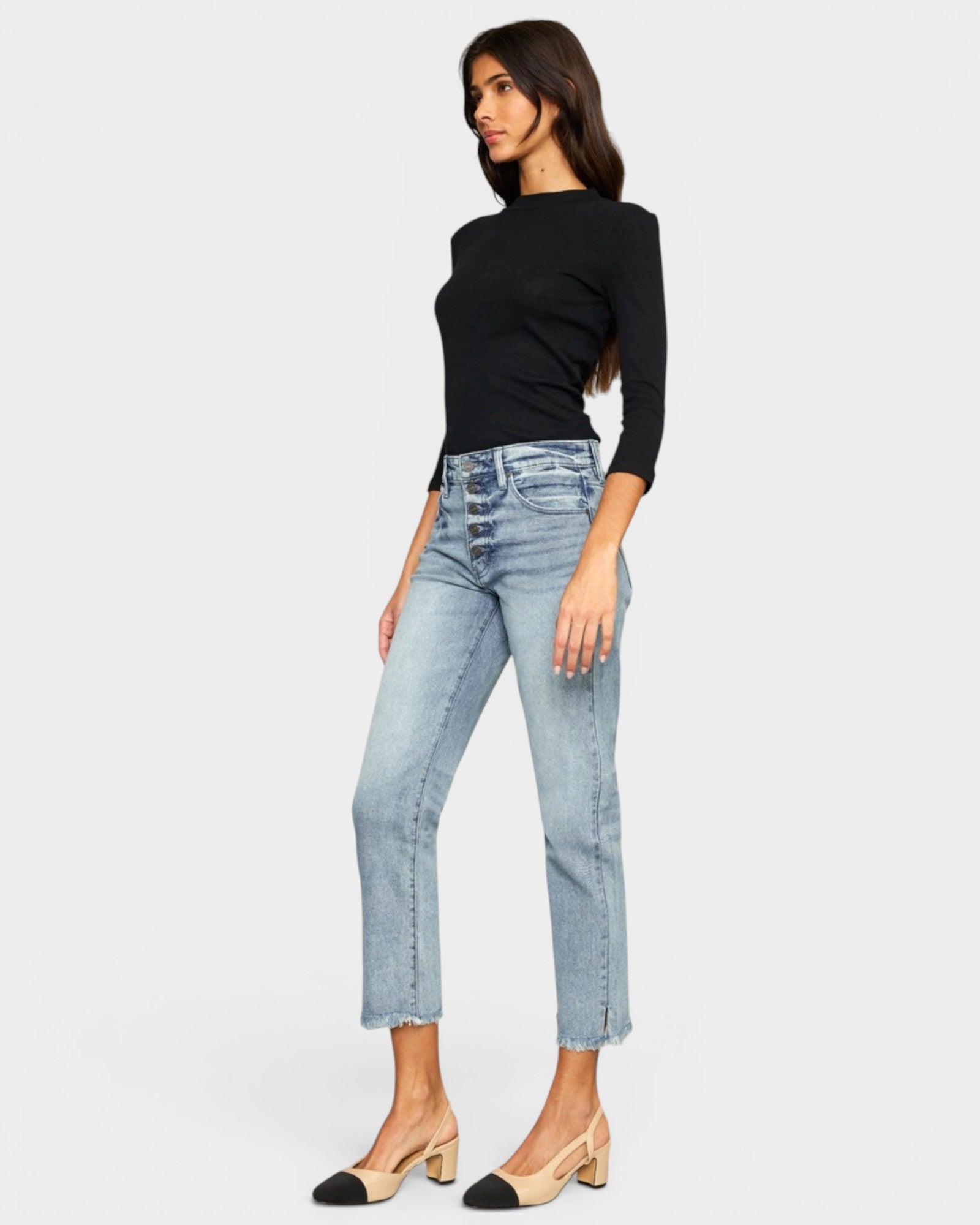 Woman wearing light blue jeans and a black top on a white background
