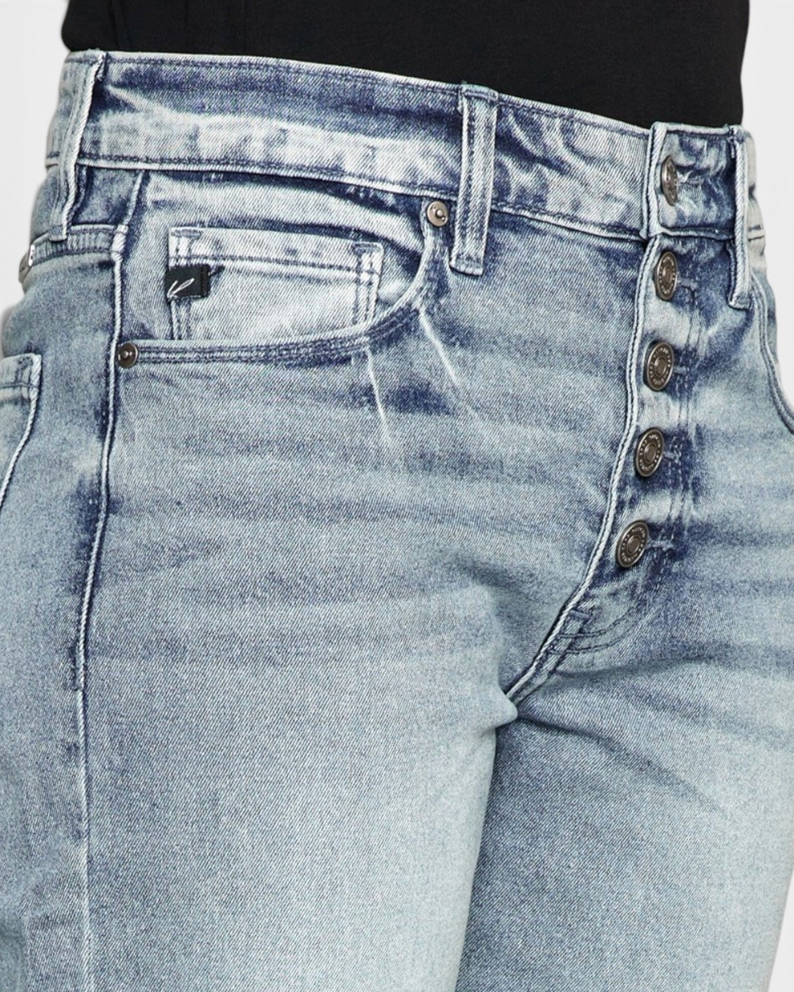 Close-up of light blue jeans with button details on a white background