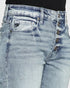 Close-up of light blue jeans with button details on a white background