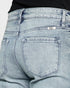 Close-up of light blue denim jeans with a brand label on a plain background