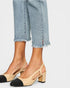 Beige and black block-heel shoes worn with light blue jeans on a white background