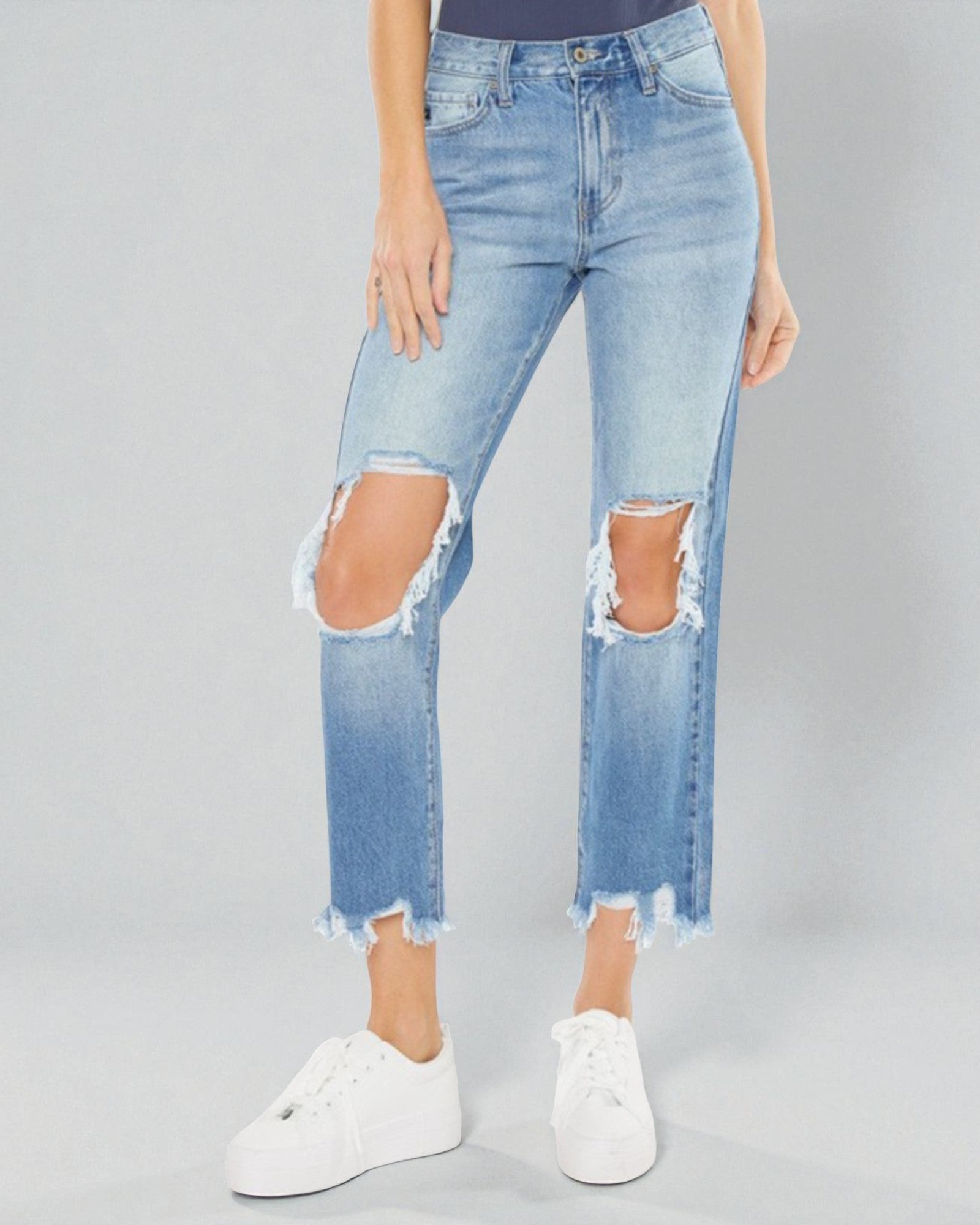 Person wearing light blue distressed jeans on a gray background