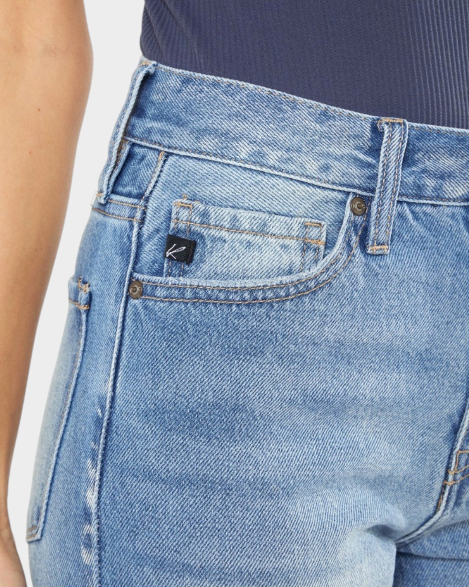 Close-up of blue jeans with a brand logo on the pocket against a white background