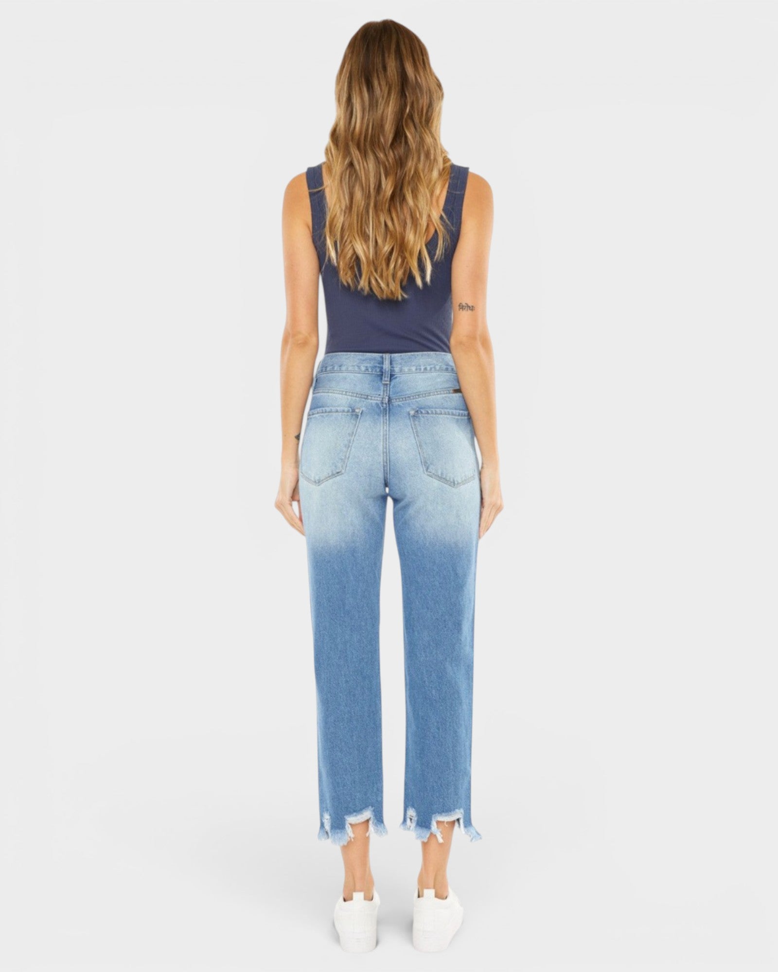 Woman wearing blue jeans and a dark top on a white background