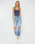Woman wearing a navy tank top and light blue ripped jeans on a white background