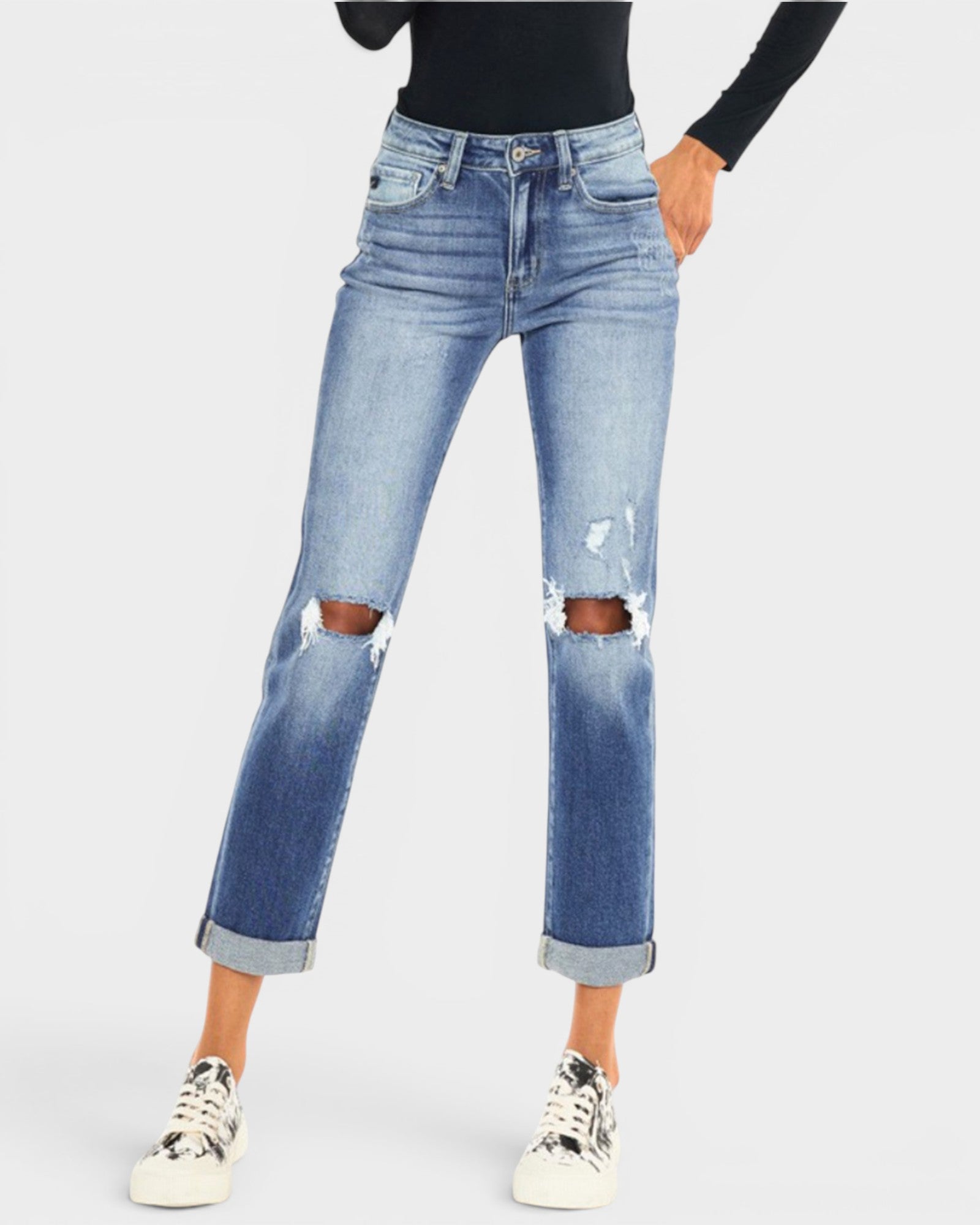 Person wearing distressed blue jeans on a white background