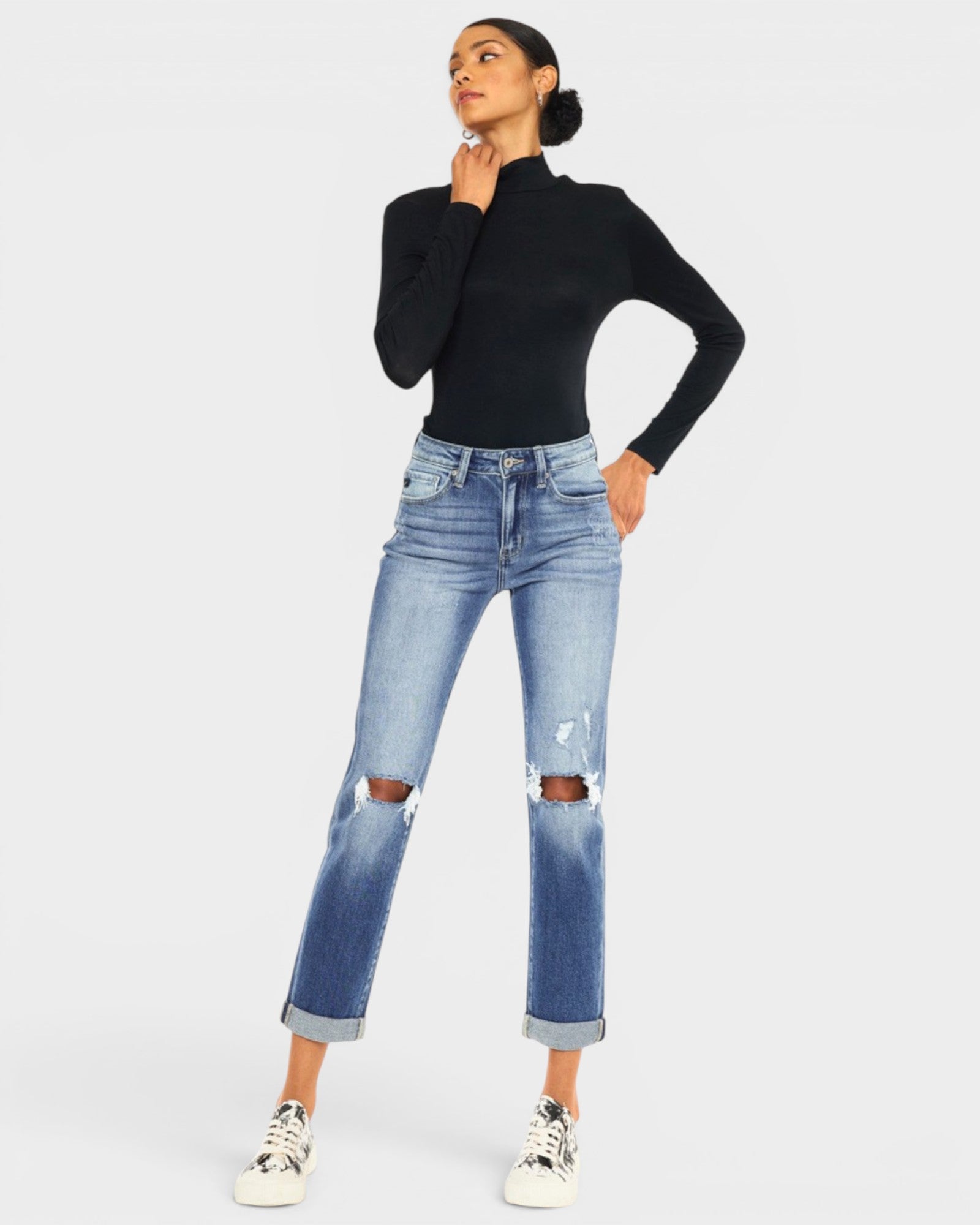 Person wearing a black turtleneck and light blue jeans on a white background