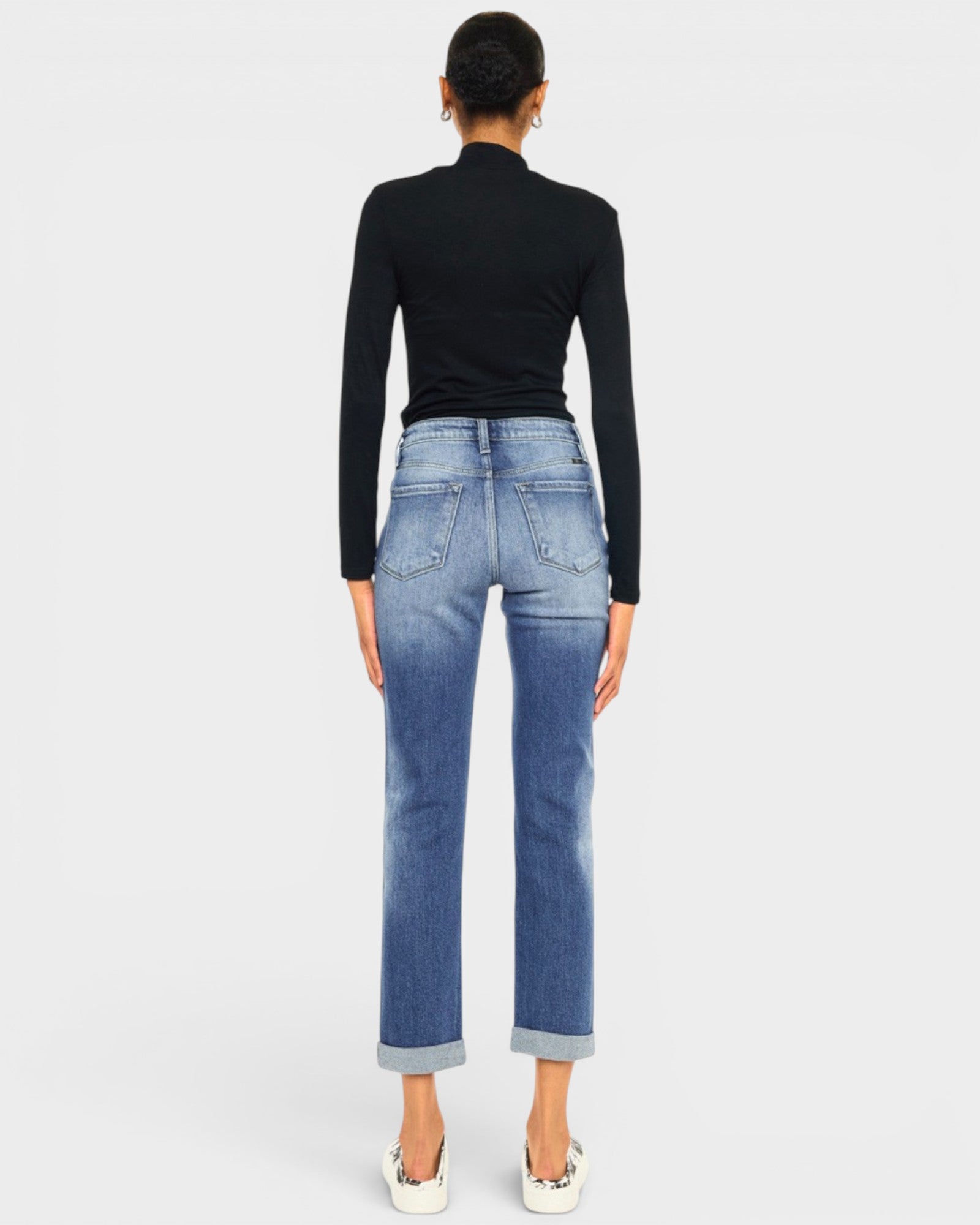 Person wearing blue jeans and a black top on a white background