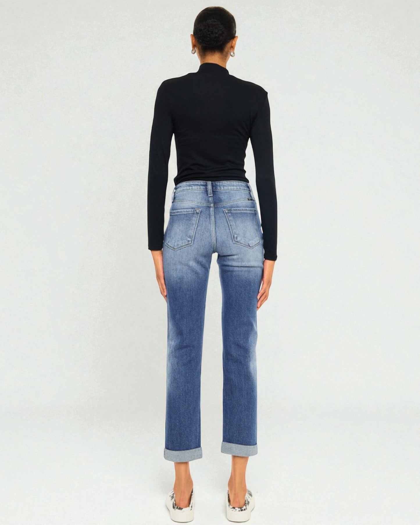 Person wearing blue jeans and a black top on a white background