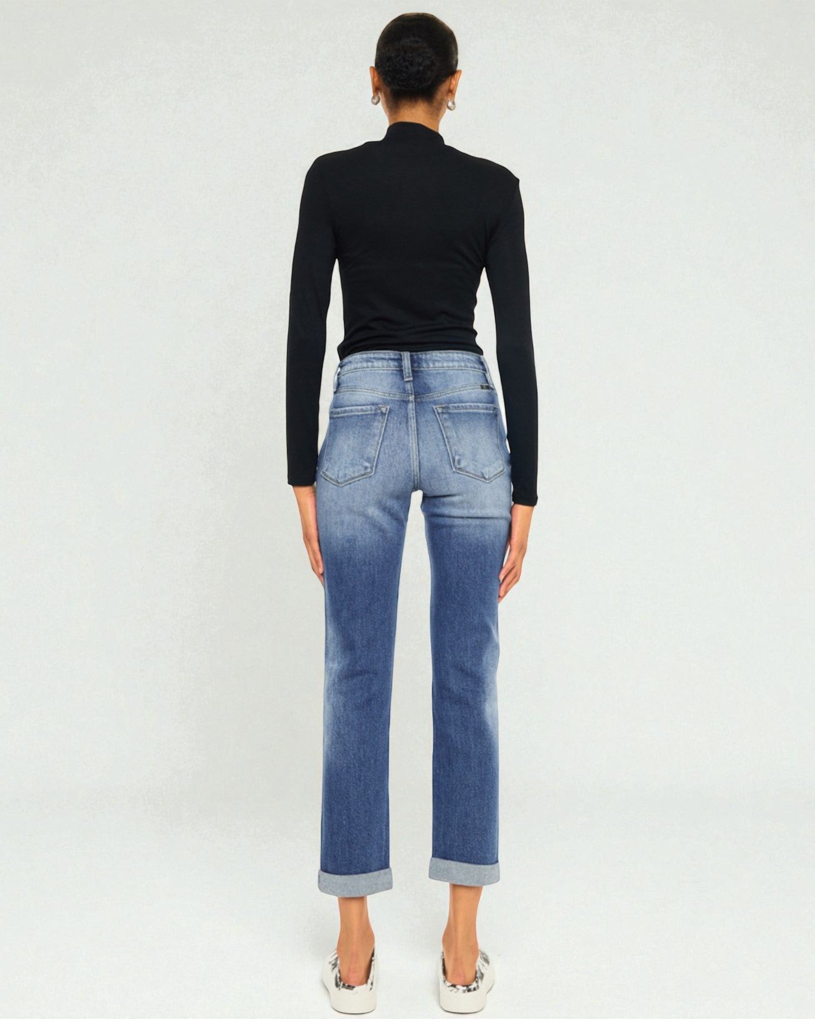 Person wearing blue jeans and a black top on a white background