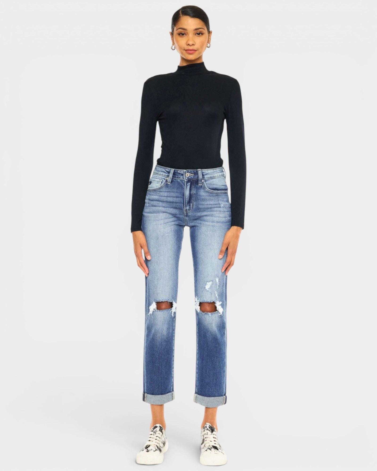 Person wearing a black turtleneck and blue jeans on a white background