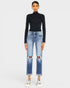 Person wearing a black turtleneck and blue jeans on a white background