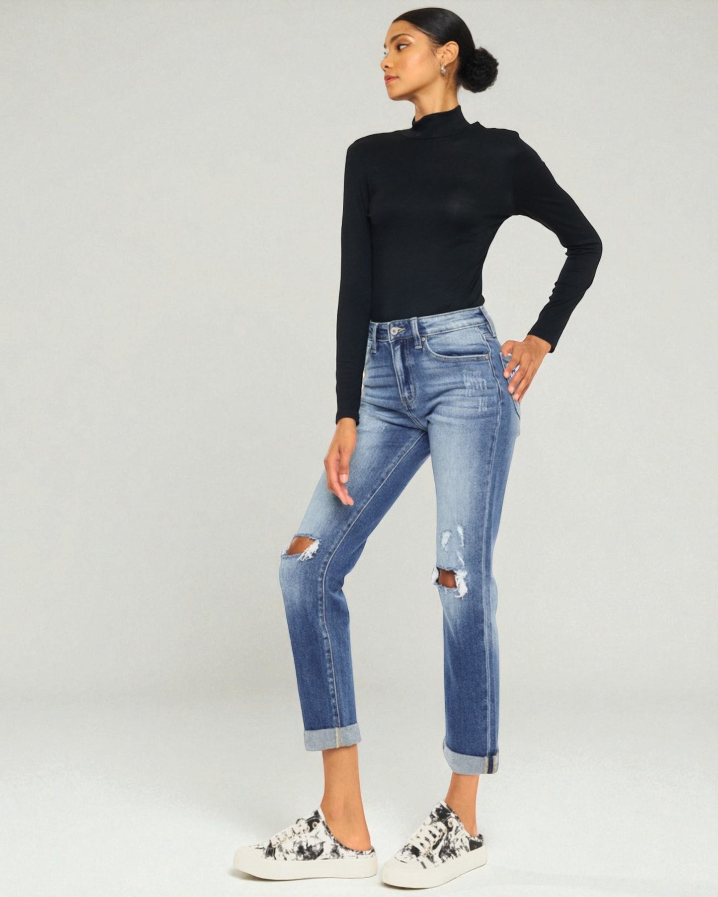 Woman wearing a black turtleneck and blue jeans on a white background