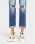Ripped blue jeans worn by a person on a white background