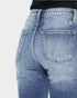 Close-up of blue jeans with a visible brand label on a light gray background